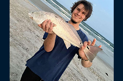 Caleb+Harris+holding+a+fish+on+the+beach